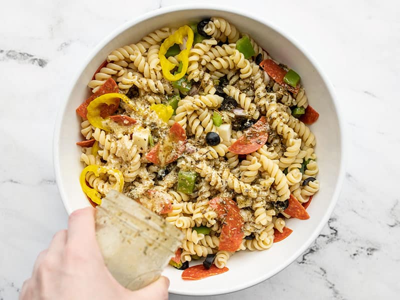 Italian dressing being poured over pasta salad