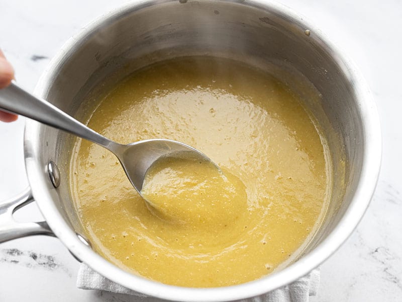 A spoon dipping into the finished green enchilada sauce in the sauce pot