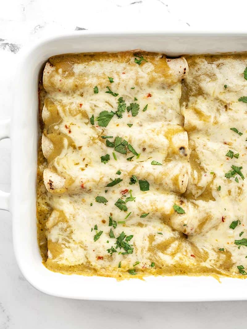 Close up overhead view of green chile chicken enchiladas in a casserole dish