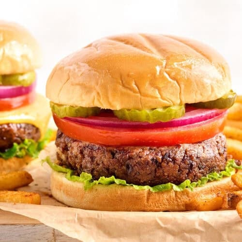 Side view of a black bean burger in a hamburger bun with toppings.
