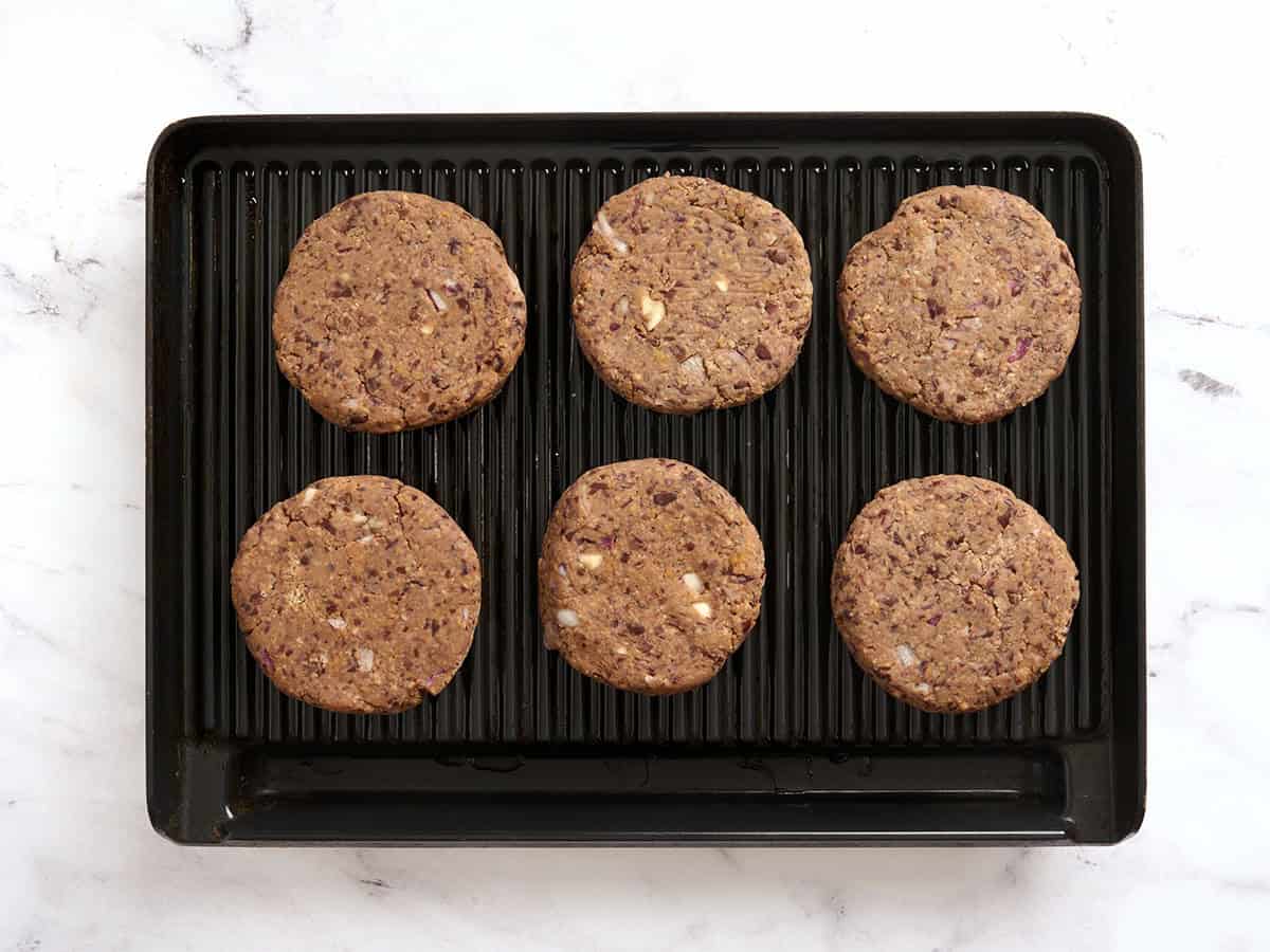 Black bean patties added to a hot grill.