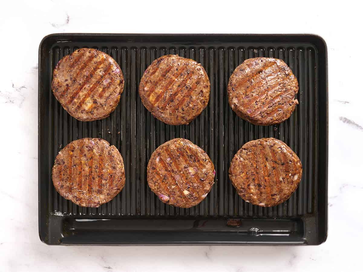 Finished black bean burgers on a grill.
