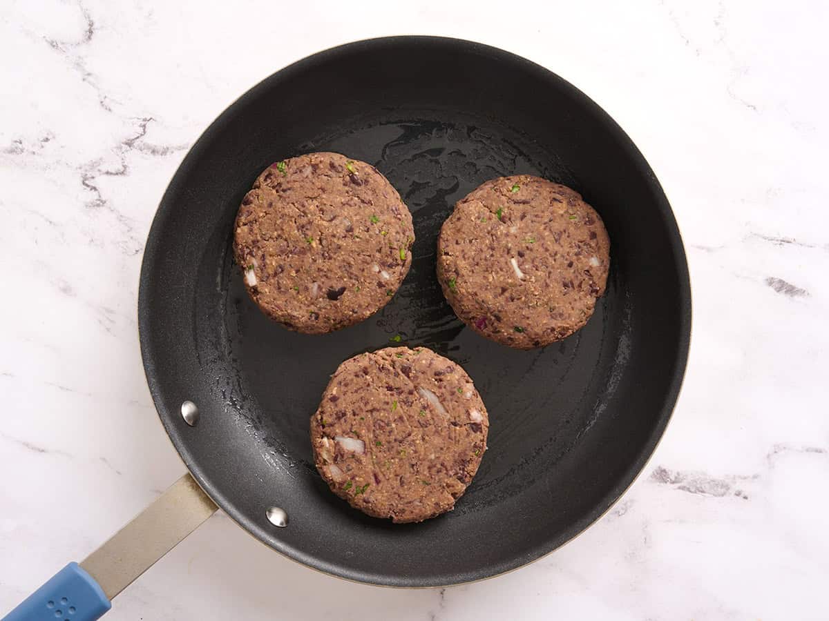 Black bean burgers cooking in a skillet.