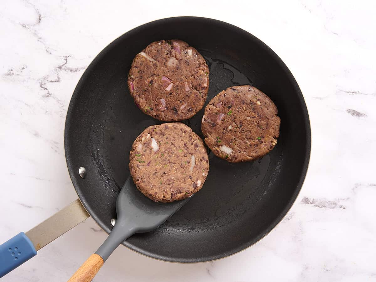 Black bean burgers after being flipped in a skillet.