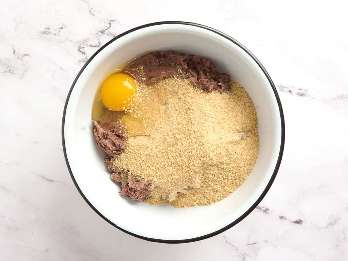Breadcrumbs and egg in a bowl with black bean mixture.