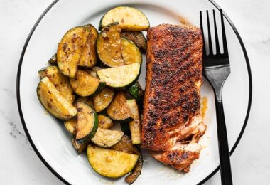 Blackened salmon with zucchini on a plate with a black fork on the side