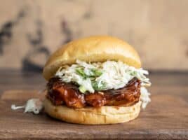 Front view of a single Easy BBQ Chicken Sandwich on a wooden cutting board