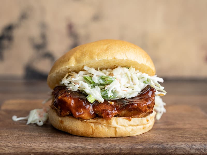 Front view of a single Easy BBQ Chicken Sandwich on a wooden cutting board