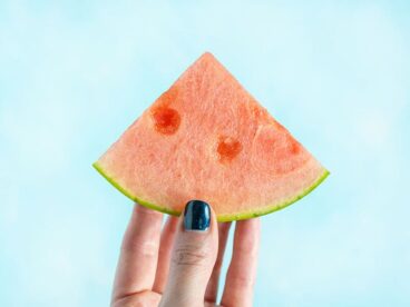 A hand holding a wedge of watermelon