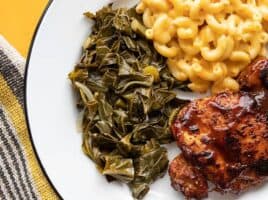 jerk seasoned collard greens on a plate with mac and cheese and bbq chicken
