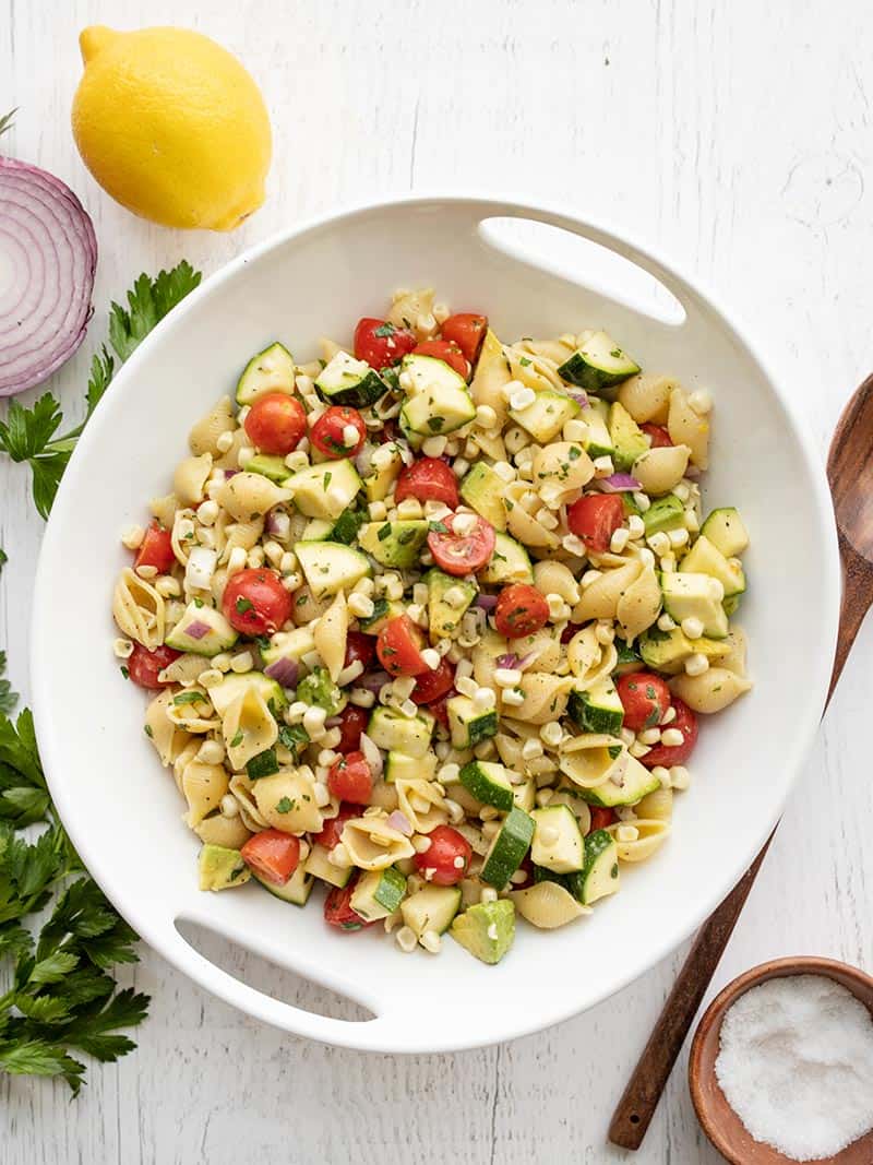 Colorful summer vegetables, creamy avocado, pasta shells, and a homemade lemon vinaigrette make this light and fresh Summer Sweet Corn Salad. Budgetbytes.com Overhead view of a serving bowl full of Summer Sweet Corn Salad