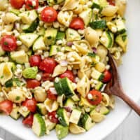 Close up of a bowl of Summer Sweet Corn Salad with a wooden spoon in the middle