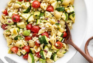 Close up of a bowl of Summer Sweet Corn Salad with a wooden spoon in the middle