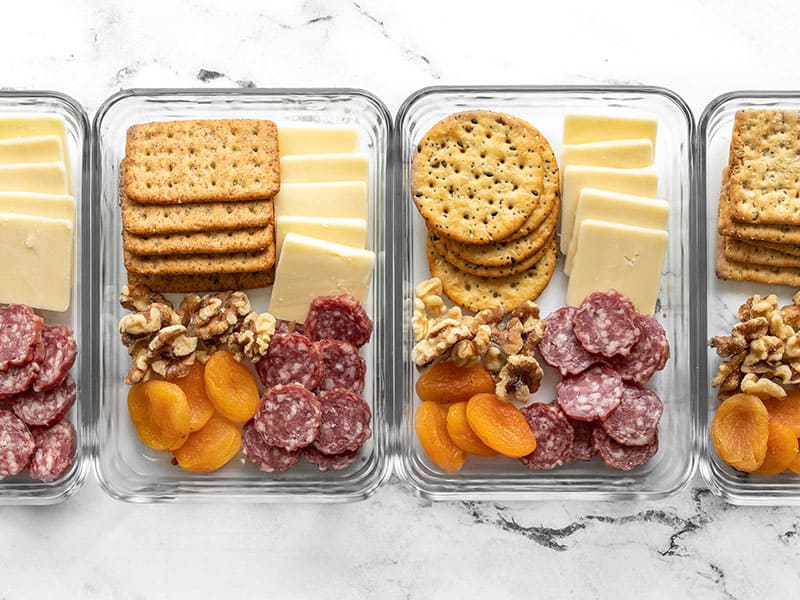 Four cheese board lunch boxes lined up in a row