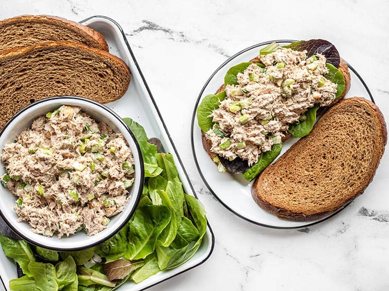 Tuna salad sandwich next to a tray with sandwich fixings