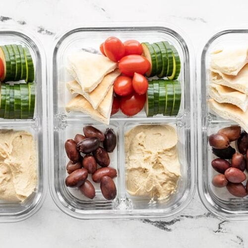 Three glass containers filled with hummus lunch box ingredients
