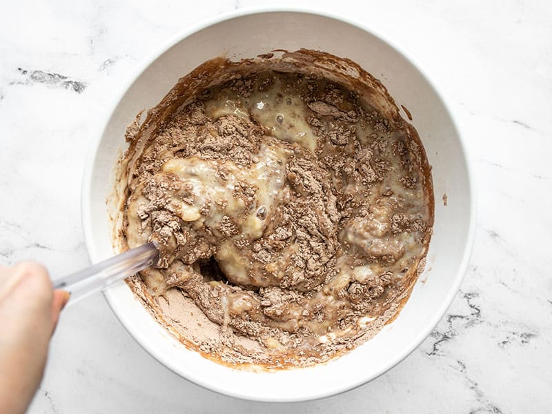 wet and dry ingredients being stirred together with a spatula