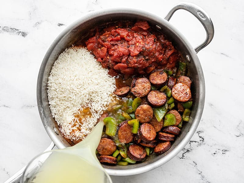 Tomatoes, rice, and broth added to the skillet