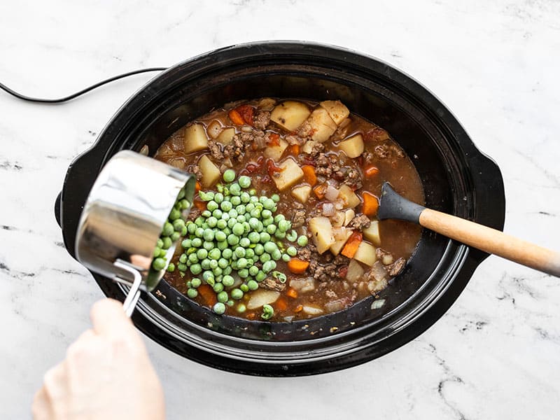 Frozen peas being added to the slow cooker