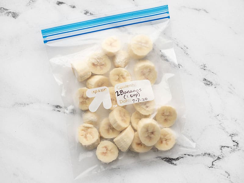 Frozen banana slices in a labeled freezer bag