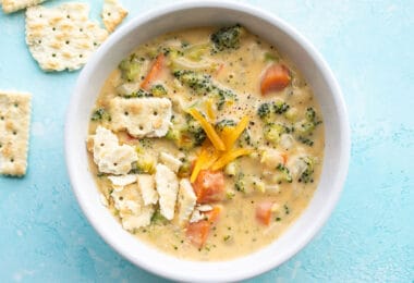 Overhead view of a bowl of broccoli cheddar soup with saltine crackers