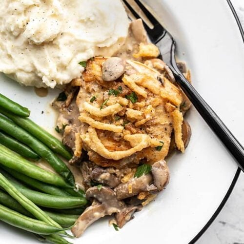 Creamy mushroom chicken on a plate with mashed potatoes and green beans