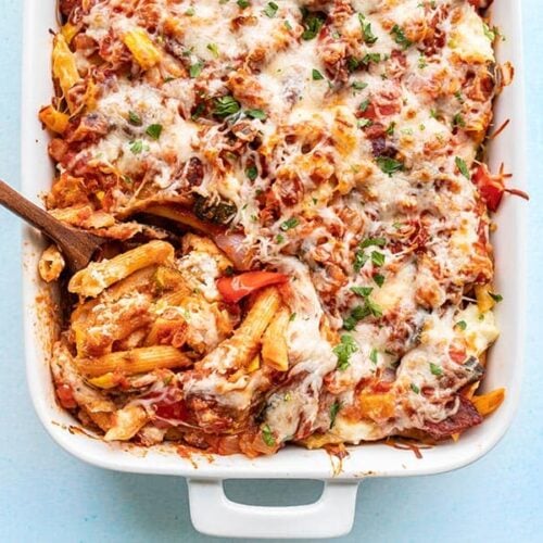 Overhead view of roasted vegetable baked penne being scooped out of the casserole dish