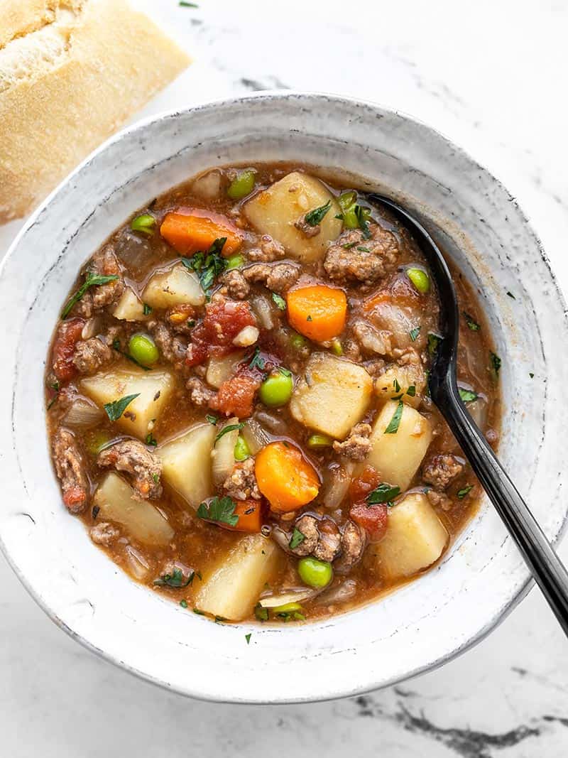 Overhead view of a bowl of slow cooker hamburger stew with bread on the side