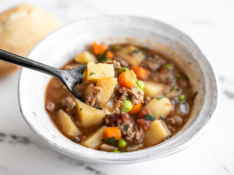 Slow Cooker Hamburger stew in a bowl with a spoon lifting a bite
