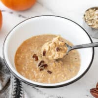 Side view of a spoon lifting some pumpkin pie overnight oats out of the bowl