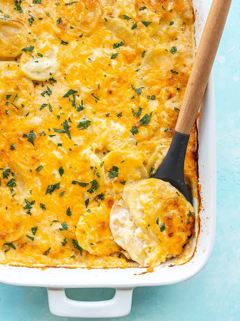 Thinly sliced potatoes baked in a creamy, cheesy sauce makes these Potatoes Au Gratin pure heaven in a casserole dish. Budgetbytes.com Potatoes au Gratin being scooped out of the casserole dish
