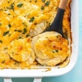 Close up overhead view of potatoes au gratin being scooped out of the casserole dish.