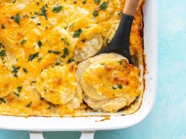 Close up overhead view of potatoes au gratin being scooped out of the casserole dish.