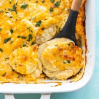 close up of potatoes au gratin being scooped out of the casserole dish