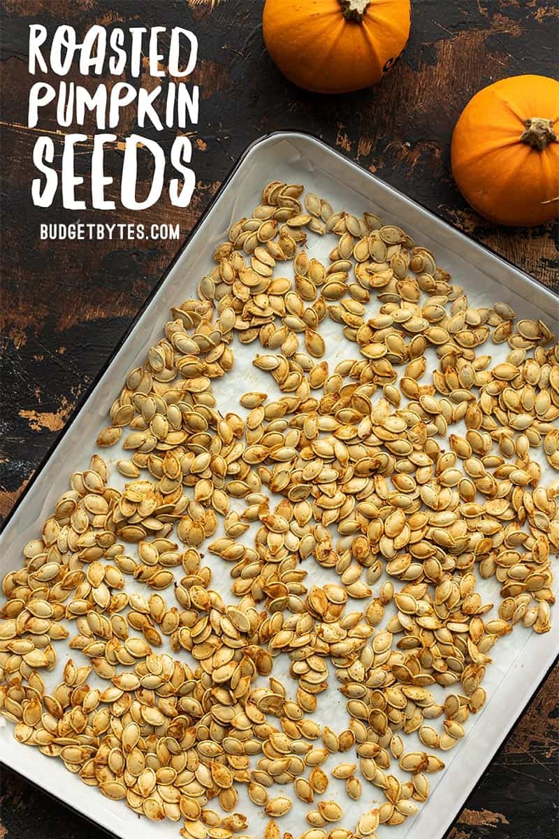 Roasted pumpkin seeds on a baking sheet with title text in the corner