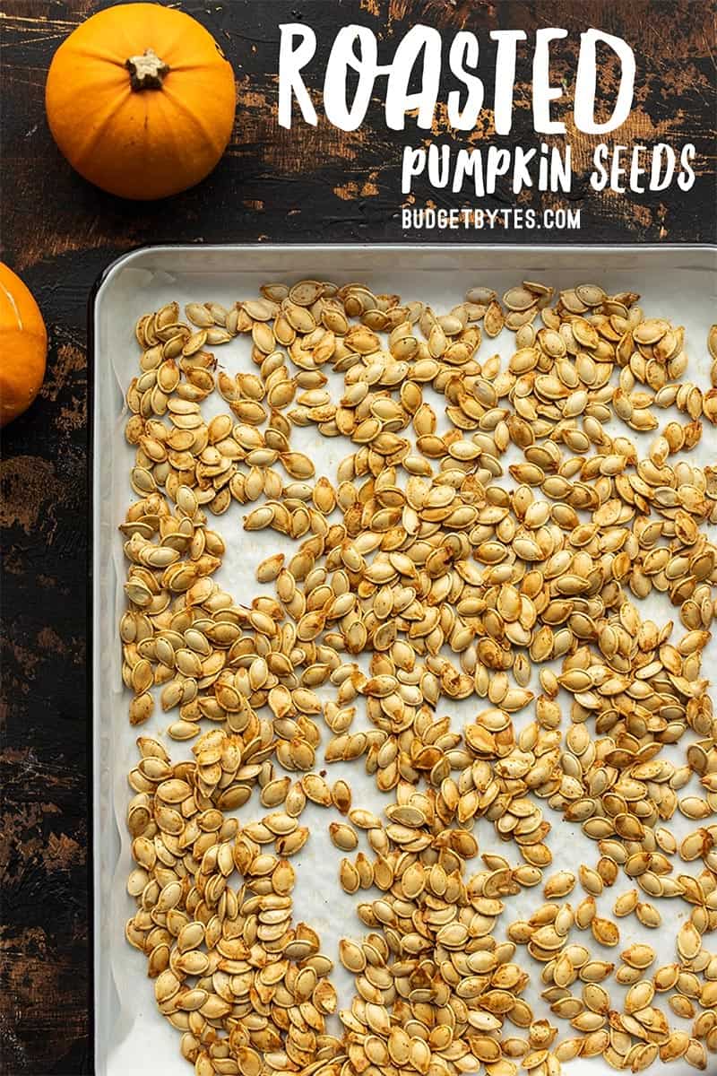 Roasted pumpkin seeds on a baking sheet with title text at the top