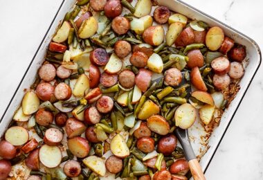 Sheet pan roasted kielbasa potatoes and green beans with a spatula