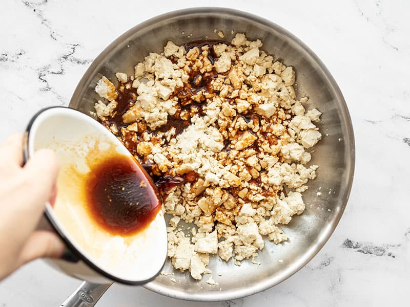 sauce being added to cooked tofu in the skillet