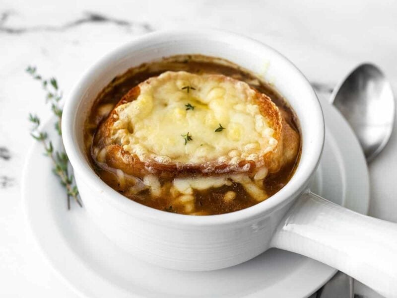 Side view of a bowl of French Onion Soup garnished with fresh thyme