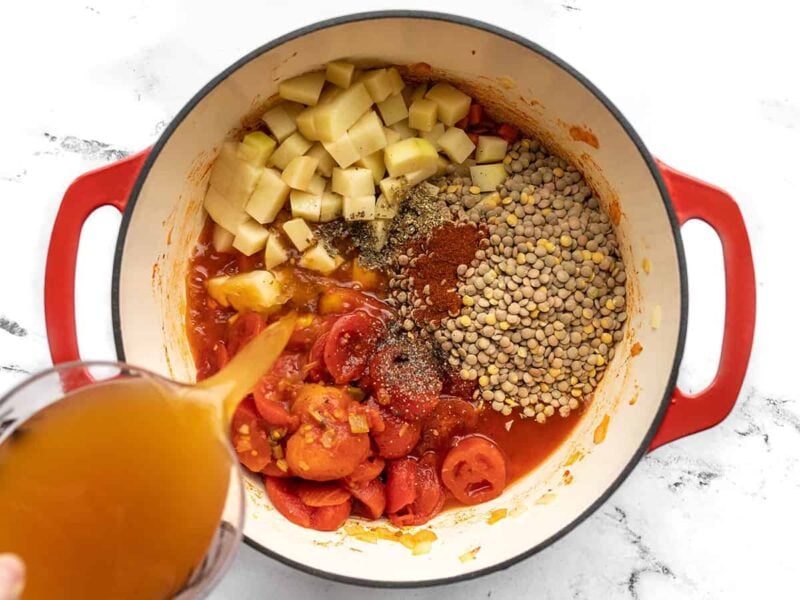 Batatas, lentilhas, tomates, temperos e caldo adicionados à panela