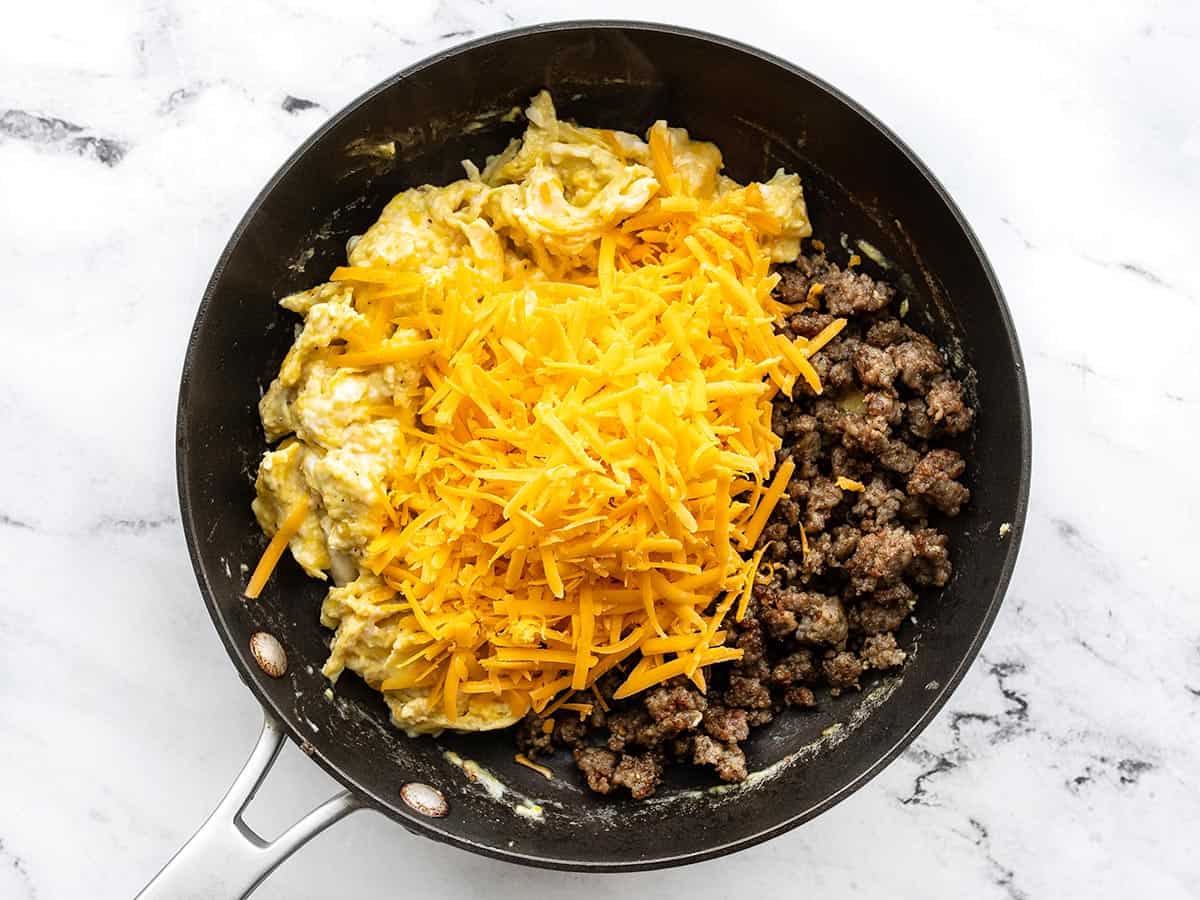 Sausage and cheese added to the skillet with the eggs