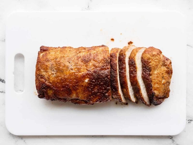 Sliced brown sugar roasted pork loin on a cutting board