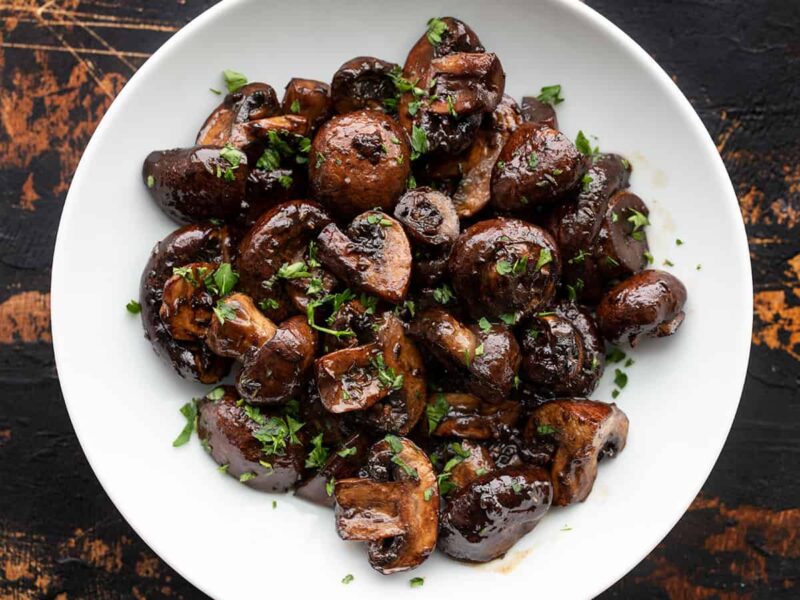 Overhead view of balsamic roasted mushrooms in a bowl garnished with chopped parsley