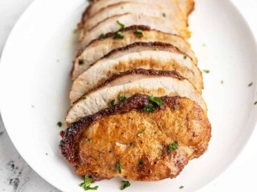 Sliced brown sugar pork loin on a serving dish, viewed from the front