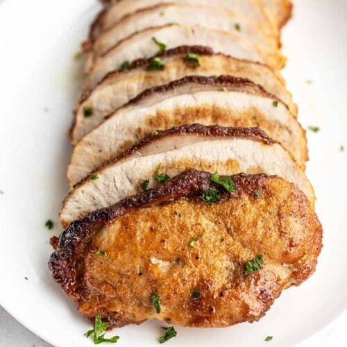 Sliced brown sugar pork loin on a serving dish, viewed from the front