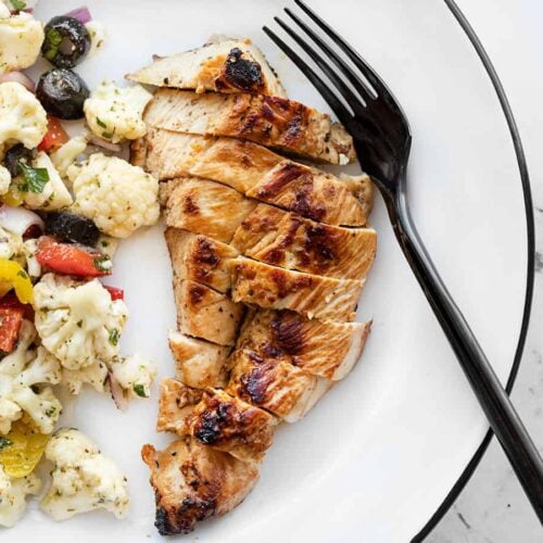 Sliced garlic marinated chicken on a plate with a fork