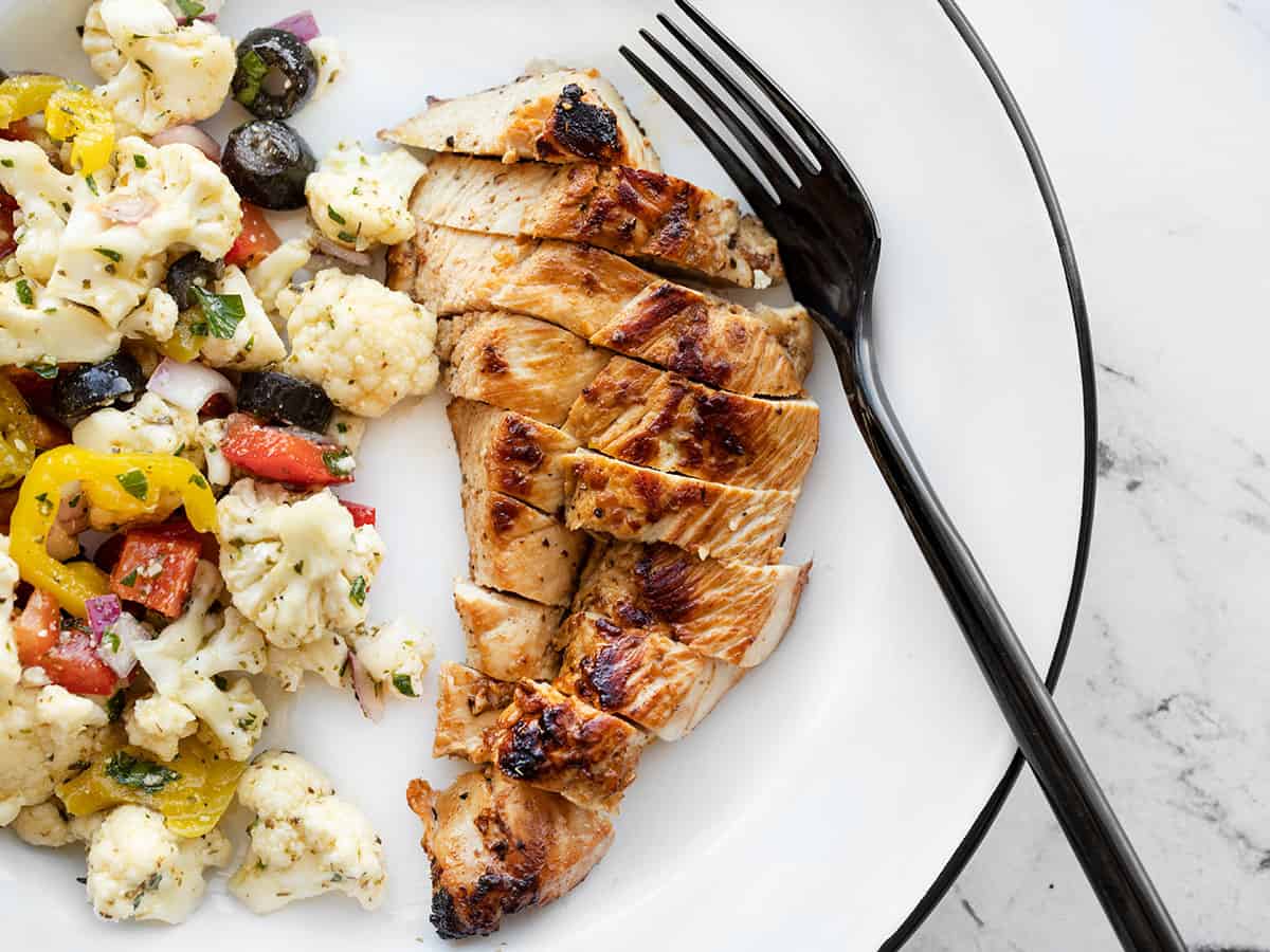 Sliced garlic marinated chicken on a plate with a fork