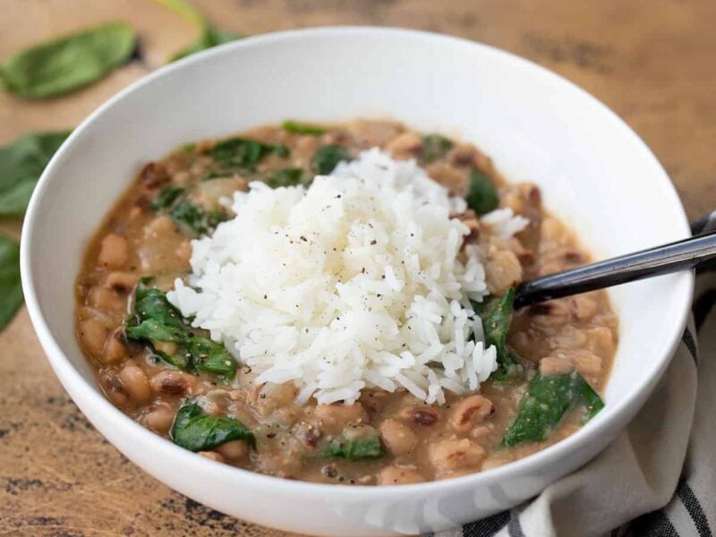 Side view of a bowl of black eyed peas with greens and rice