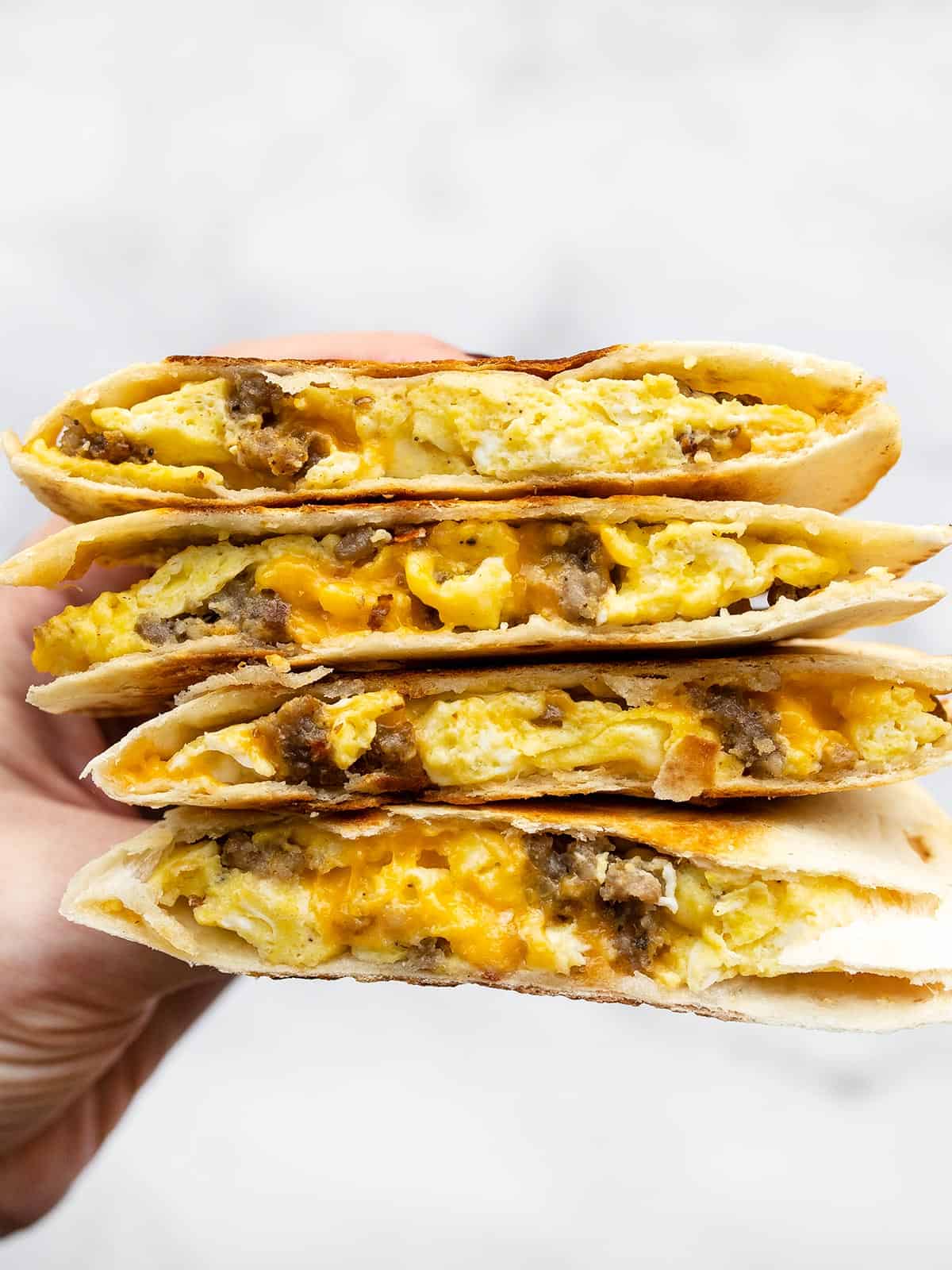 Stacked sausage and egg breakfast quesadillas held close to the camera