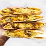 Stacked sausage and egg breakfast quesadillas held close to the camera